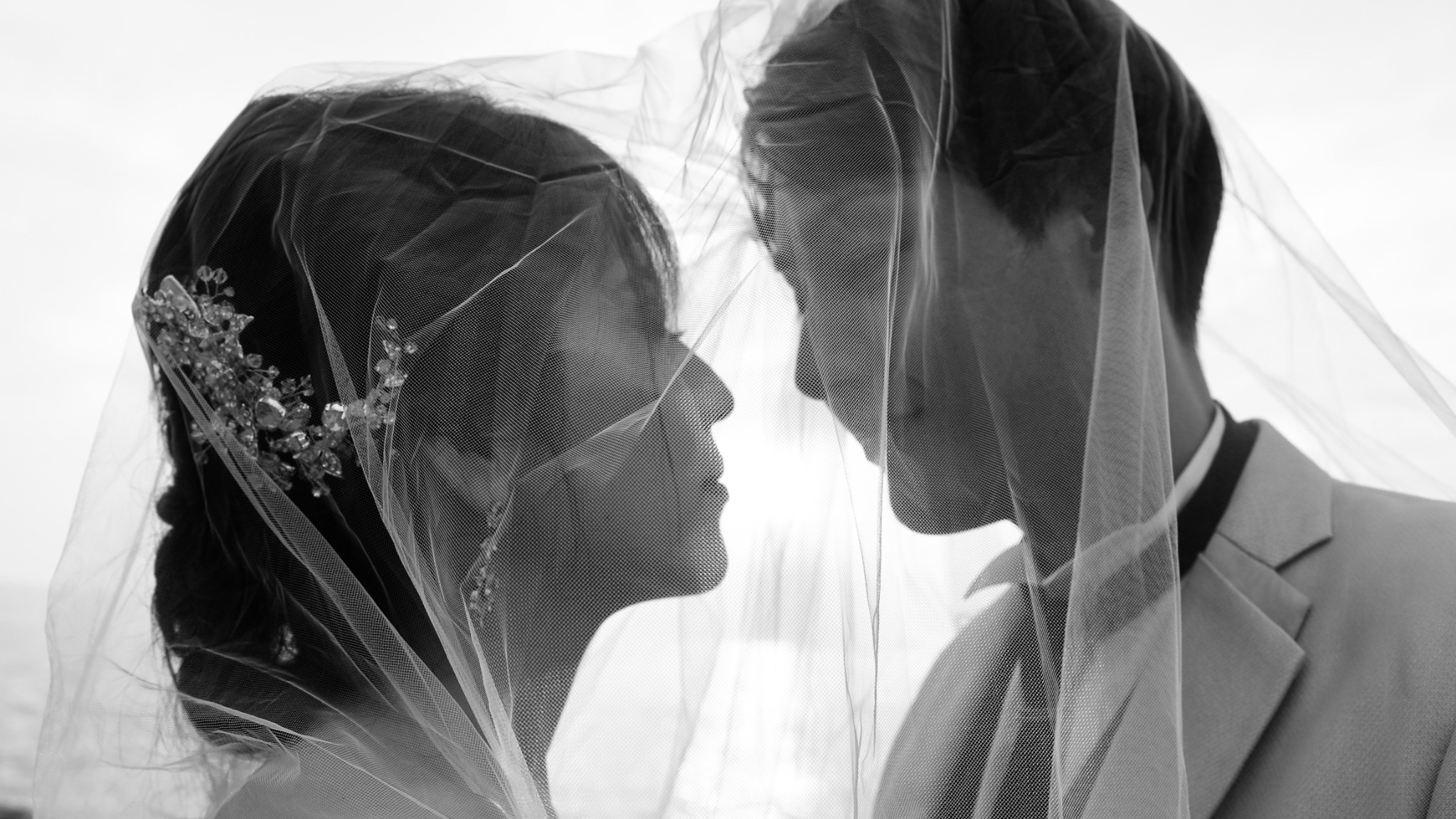 ベール越しに見つめ合う新郎新婦のモノクロ写真
